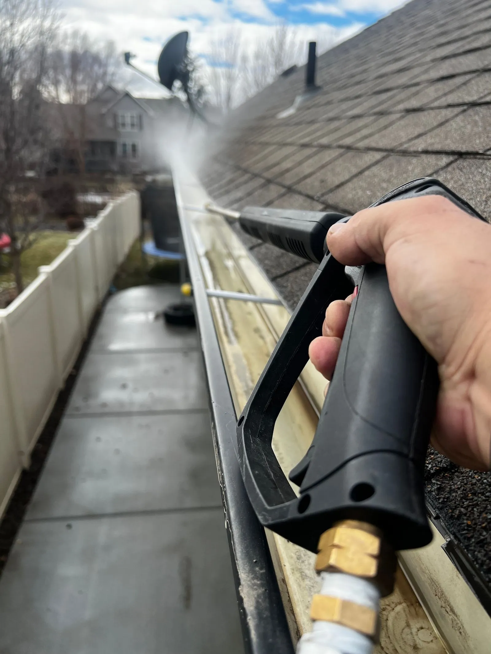 A gutter along a home roofline being rinsed clean