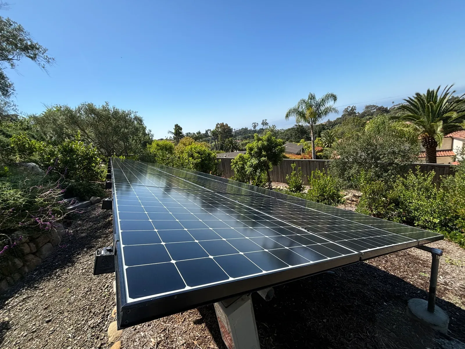 A ground-mounted solar panel array cleaned to a clear finish in a lush Santa Barbara garden